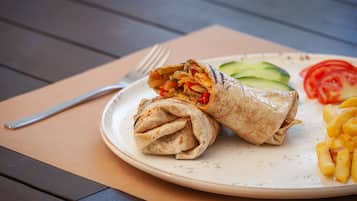 A plate with a wrap, cucumber slices, tomato slices, and fries.