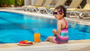A child sitting by a pool with a plate of fruit and drinks. - Golden Orange Hotel (Konyaalti)