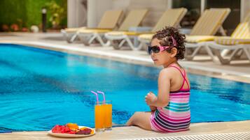 Alberca al aire libre, sombrillas en la alberca y camastros