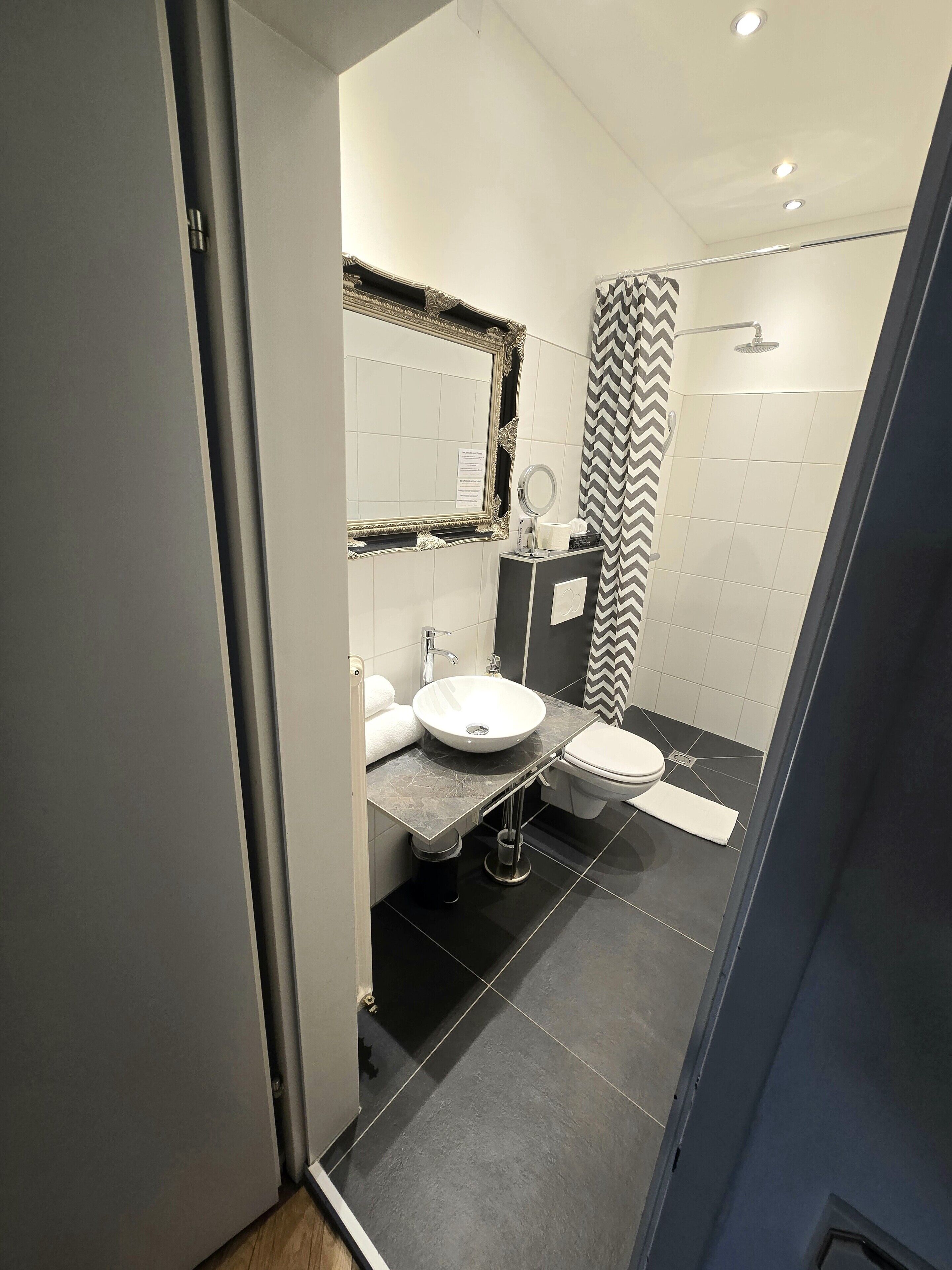 A modern bathroom with a vanity, sink, mirror, and shower.