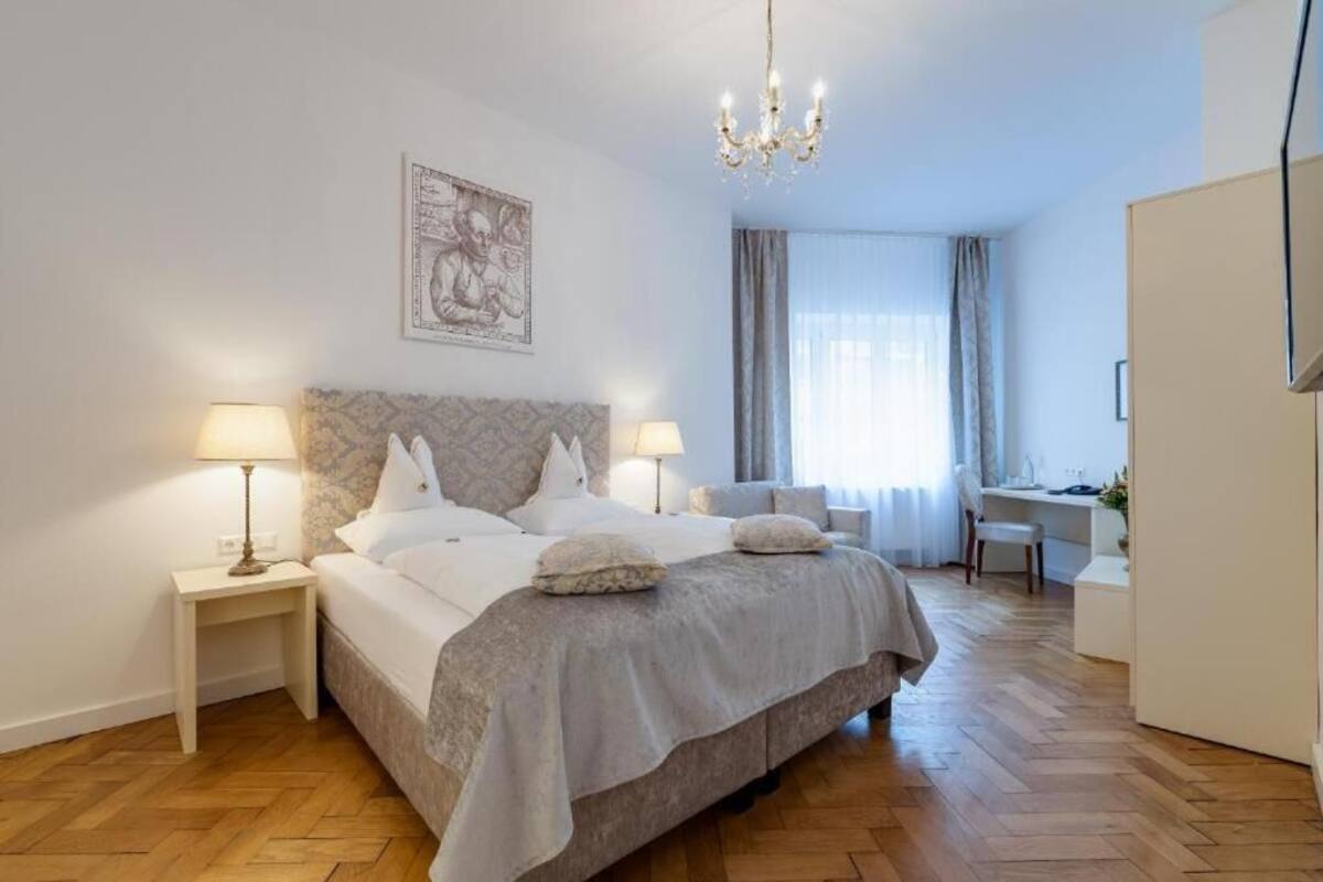 Ein Hotelzimmer mit einem großen Bett, zwei Nachttischen mit Lampen, einem Schreibtisch und einem Stuhl.