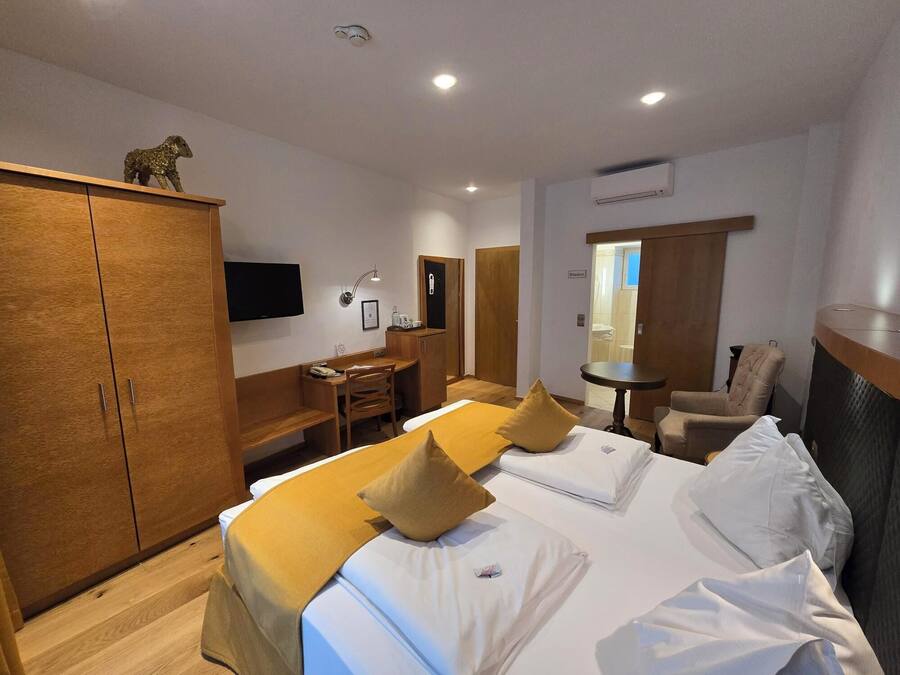 Ein Hotelzimmer mit Bett, Schreibtisch, Stuhl und Kleiderschrank.