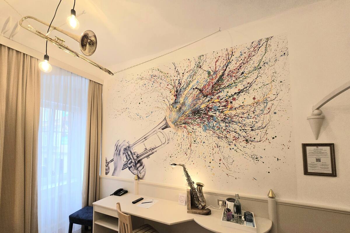 Ein Zimmer mit Schreibtisch, Stuhl und einem großen, abstrakten Gemälde an der Wand.