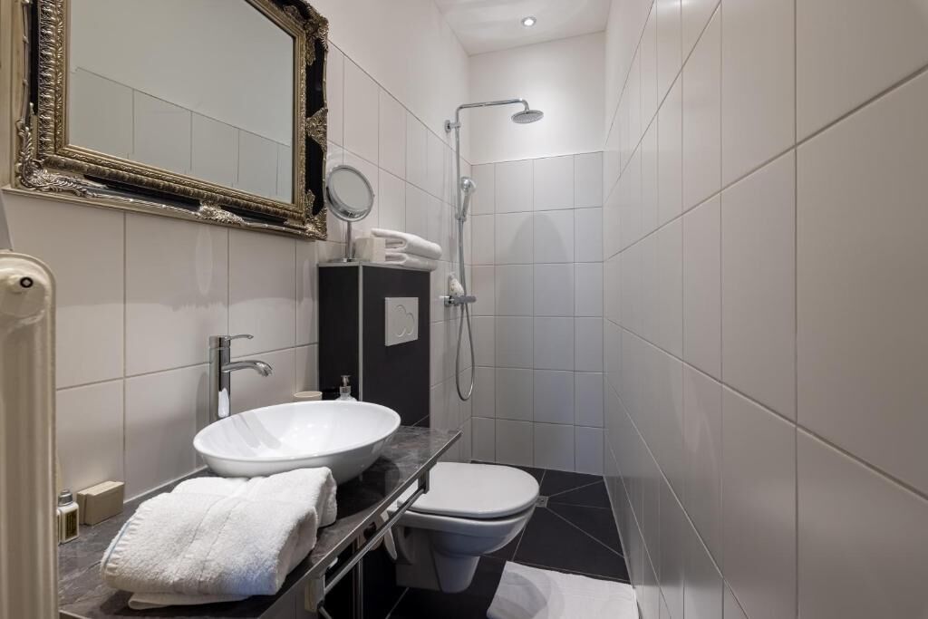 A modern bathroom with a white sink, a toilet, and a shower.