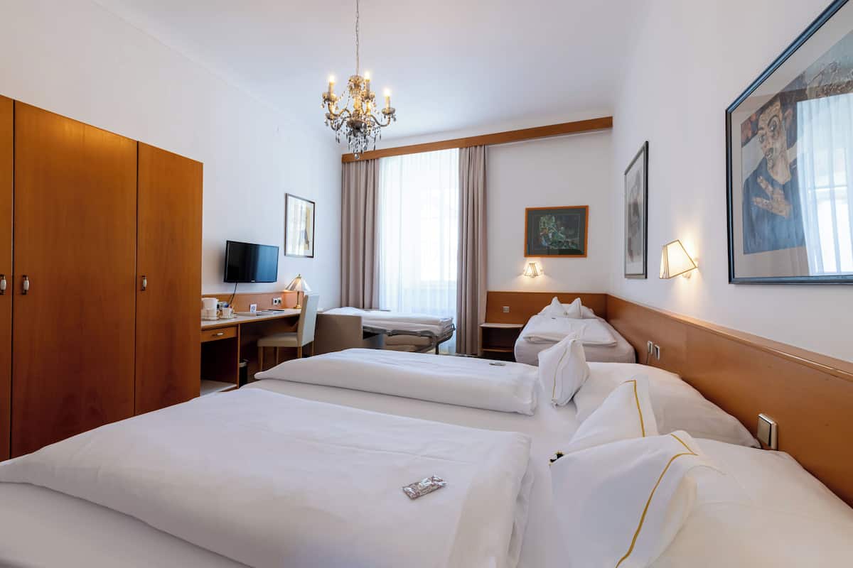 Ein Hotelzimmer mit zwei Betten, einem Schreibtisch, einem Fernseher und einem Kronleuchter.