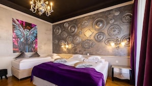 Une chambre avec deux lits, un grand mur décoratif et un lustre.