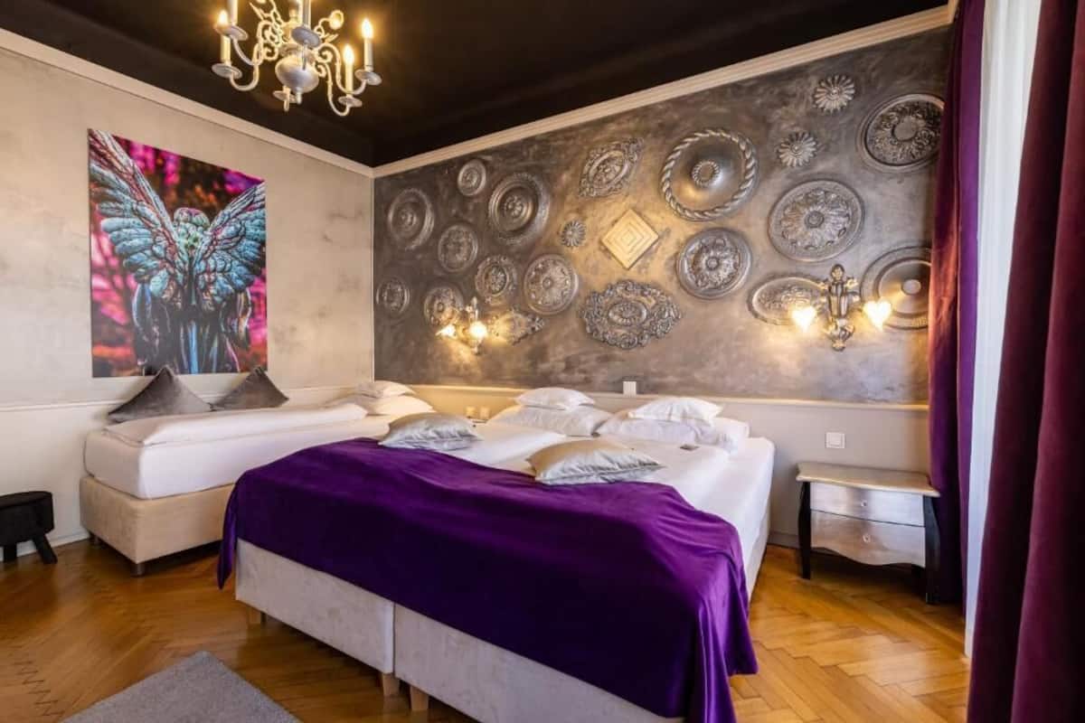 Ein Schlafzimmer mit zwei Betten, einer großen Wanddekoration und einer Chandelüster.