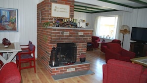A living room with a brick fireplace, red furniture, and a television. - Fjordhotell (Stryn)
