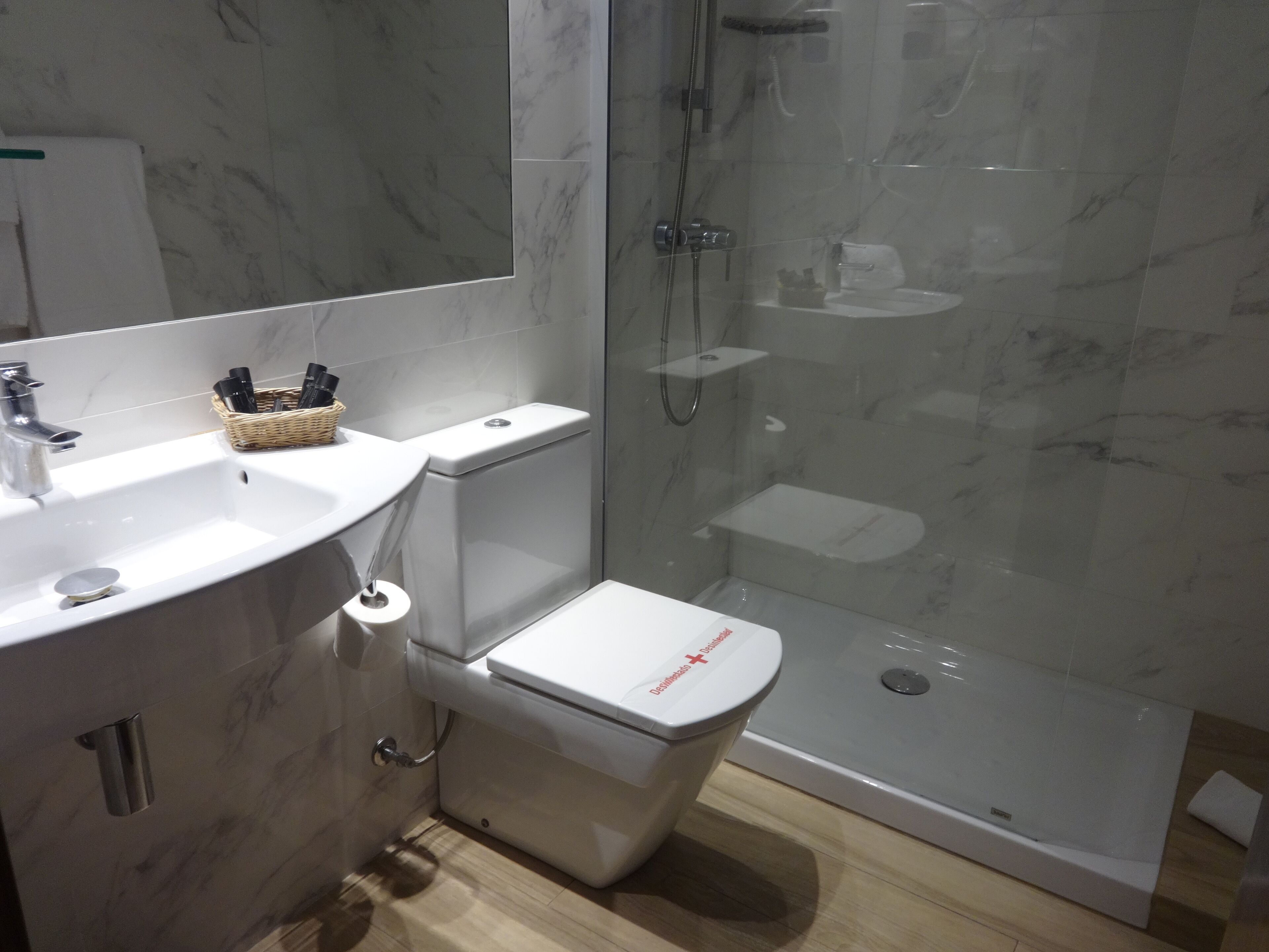 Une salle de bain moderne avec un lavabo en marbre, des toilettes et une douche à parois de verre.