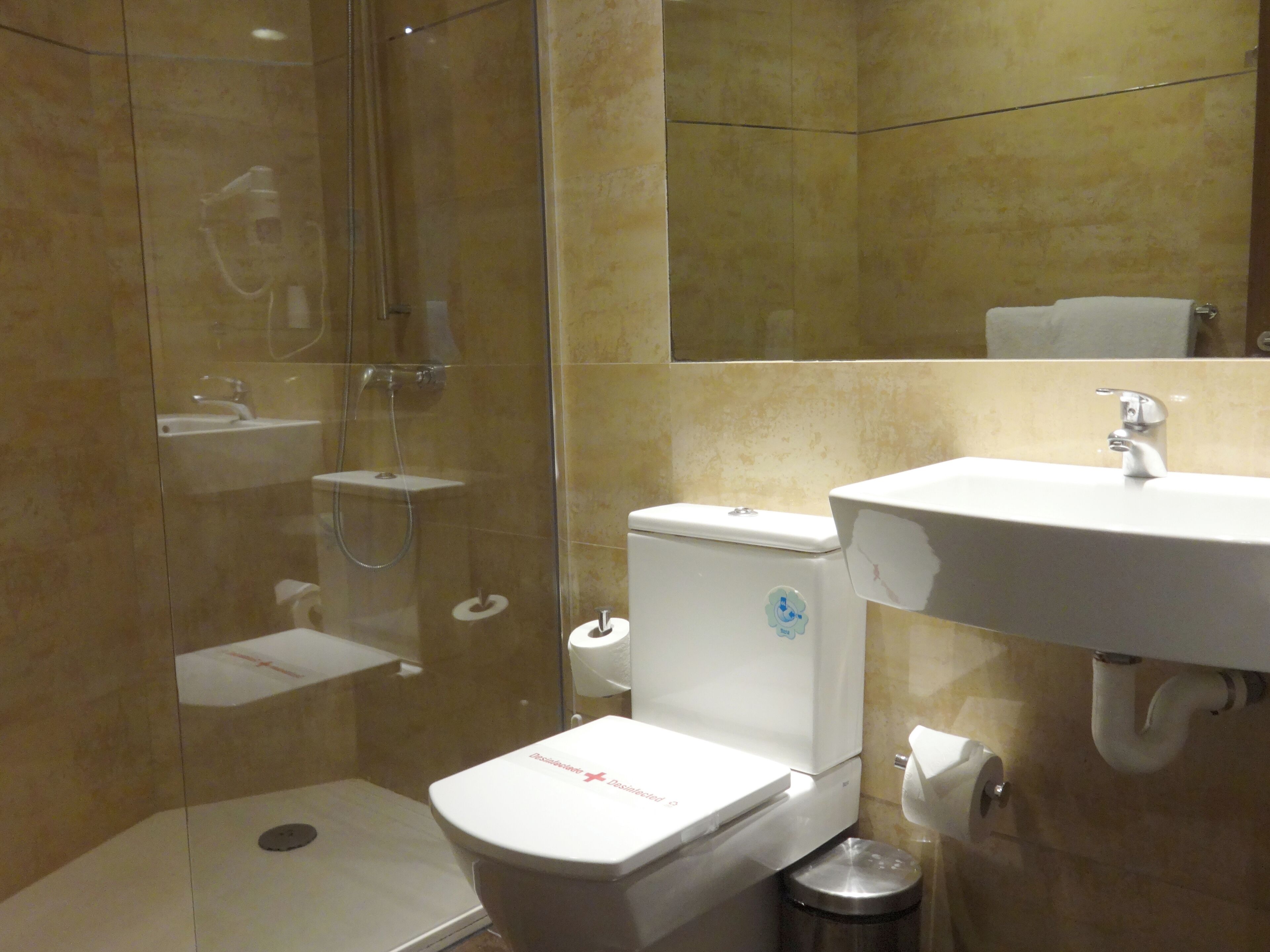 A modern bathroom with a glass-enclosed shower, a toilet, and a sink.