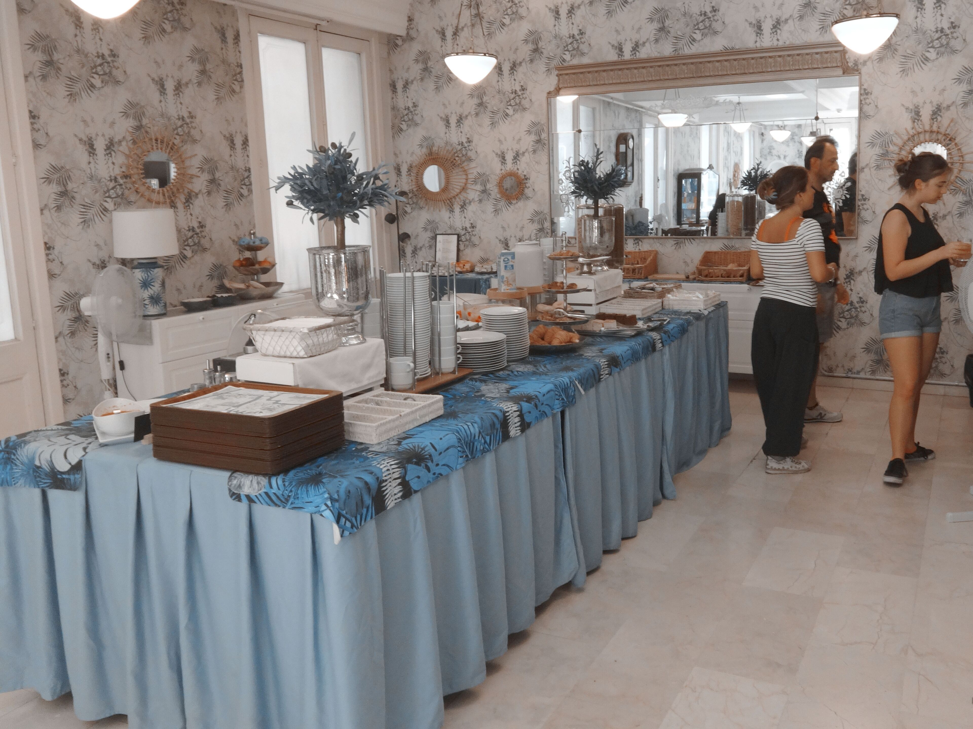 A buffet setup with various food items and serving dishes on a table covered with a blue cloth.