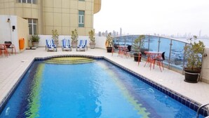 A rooftop swimming pool with lounge chairs and potted plants. - Le Royal Corniche (Salmiya)