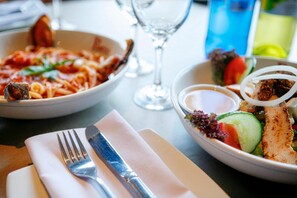 Een eettafel met spaghetti, een salade en een glas water.