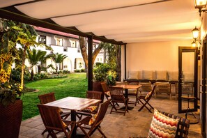 An outdoor patio with wooden furniture, a grill, and a view of a courtyard with greenery and a building. - Garden Court Polokwane (Polokwane)