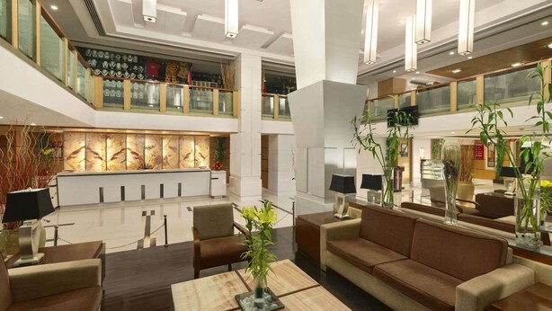 Un vestíbulo amplio con techo alto, muebles modernos y una recepción.