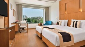 Una habitación de hotel con una cama grande, un escritorio, una silla y un televisor.