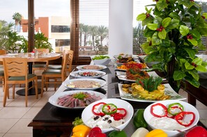 Un comedor con diversos platos, una mesa, sillas y una planta en maceta.