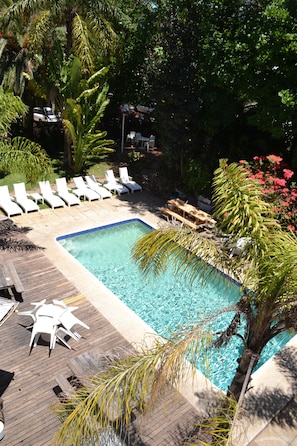 A swimming pool with lounge chairs and a wooden deck.