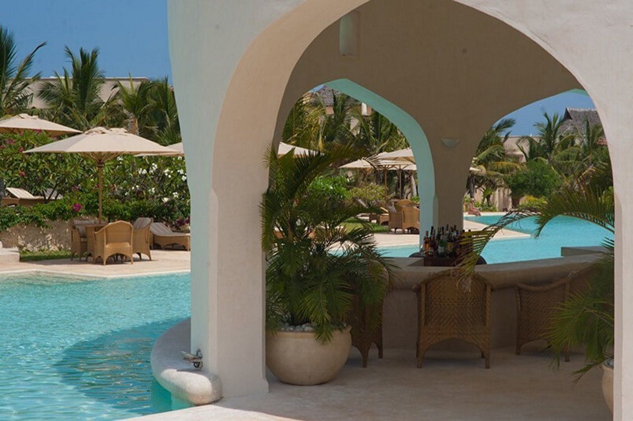 A poolside area with a lounge chair, a table with a drink basket, and a view of the pool.