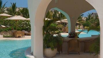 A poolside area with a lounge chair, a table with a drink basket, and a view of the pool.