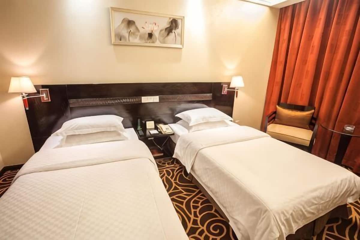 A hotel room with two beds, a nightstand, a chair, and a painting on the wall.