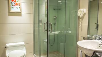 Un baño moderno con ducha acristalada, inodoro, lavabo y secador de pelo.