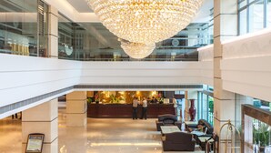 A spacious lobby with a grand chandelier, a reception desk, and seating areas. - Huashi Hotel (Guangzhou)