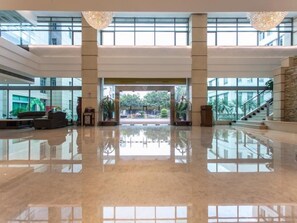 A spacious lobby with a reflective floor, large windows, and a staircase leading to upper levels. - Huashi Hotel (Guangzhou)