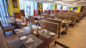 A restaurant with multiple dining booths and tables, each set with plates, cutlery, and napkins.