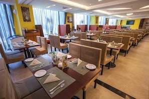 Un ristorante con diverse cabine e tavoli, ognuno apparecchiato con piatti, posate e tovaglioli.