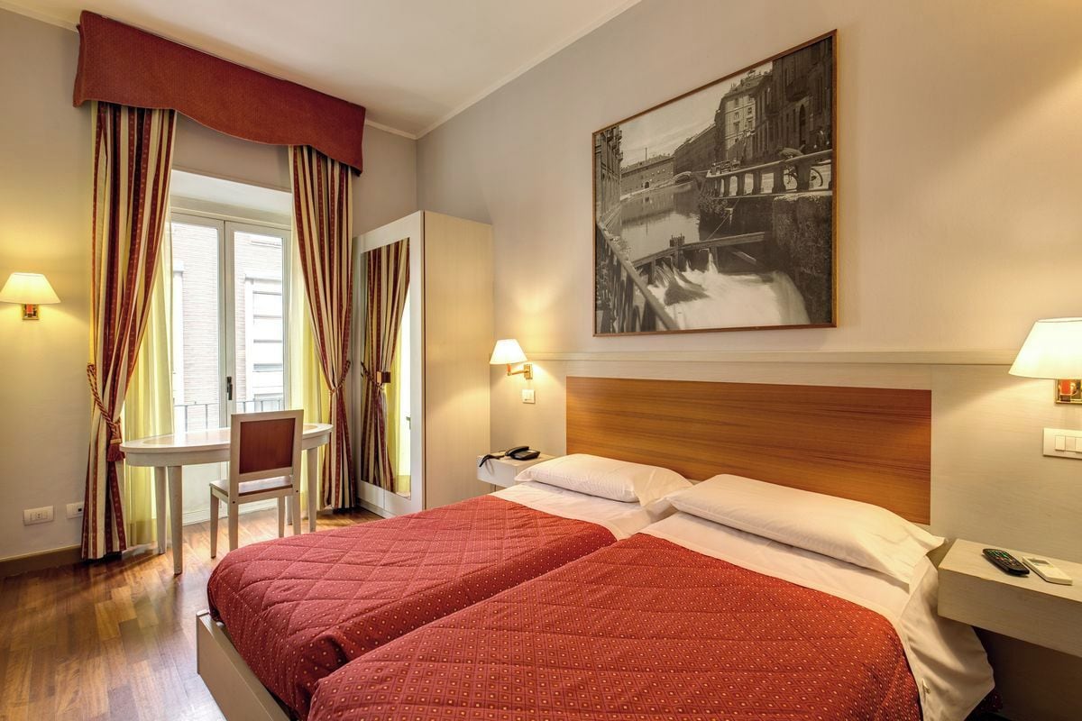 Ein Hotelzimmer mit zwei Betten, einem Schreibtisch und einem Stuhl.