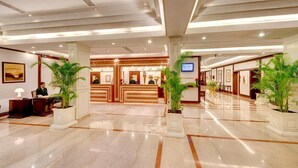 Een hotel receptie met een marmeren vloer, een receptiebalie en receptiemedewerkers.