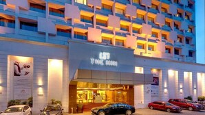 Een hotel met een moderne gevel, meerdere balkons en een goed verlichte entree.
