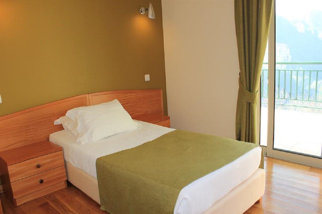 A single bed with a wooden headboard, a green throw blanket, and white bedding.