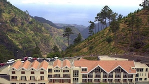 Een hotel met een symmetrische gevel, meerdere balkons en uitzicht op een bergachtig landschap.