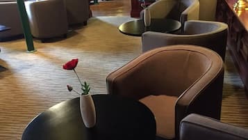 Ein Sitzbereich mit Sofas und Tischen, eine Vase mit einer Rose und ein Holzboden.
