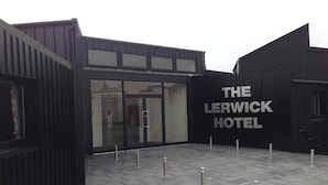 Das Hotel Lerwick mit modernem Design, ein markantes Entree mit Glasüren und einer schwarzen Fassade.