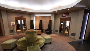 Eine Lobby mit einer Sitzgruppe in Form eines Kreises, einem Empfangstresen und einem großen Fenster.