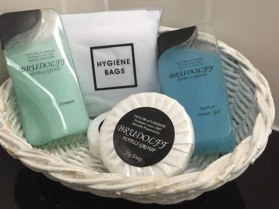 Cesto com produtos de higiene, incluindo shampoo, sachês de higiene e gel de banho, do Brudolf Hotels Group.