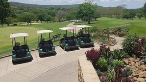 A golf course with a view of the green, a parking area with golf carts, and a landscaped garden area. - Sabi River Sun (Mbombela)