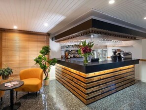 A modern bar area with a wooden counter, seating, and a glass display. - Ibis Styles Orange (Orange)