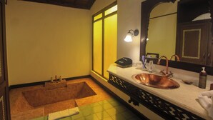A bathroom with a copper sink, a large mirror, a towel, and a bathtub. - Mesastila Resort and Spa Magelang (Losari)
