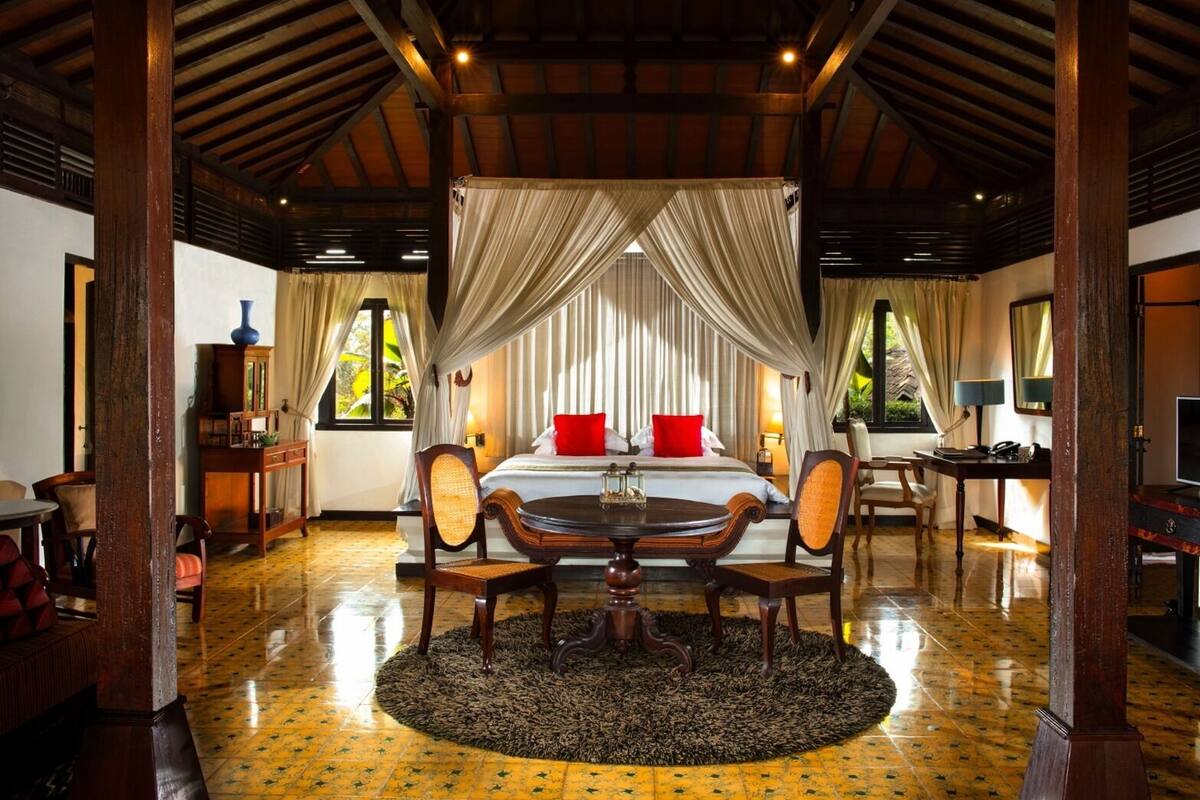 A room with a bed, a desk, a chair, a table, and a large window.