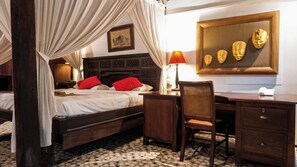 Habitación de hotel con cama, escritorio, silla y una obra de arte colgada en la pared.
