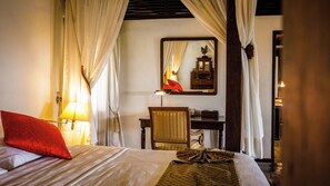 Una habitación de hotel con cama, escritorio, silla y espejo.