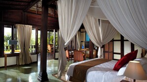 A room with a bed, a desk, and a chair. There are curtains and a window. - Mesastila Resort and Spa Magelang (Losari)