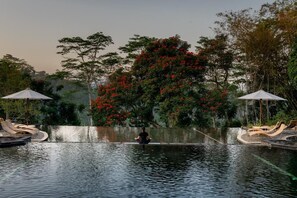 A serene outdoor pool area with lounge chairs and a person meditating. - Mesastila Resort and Spa Magelang (Losari)