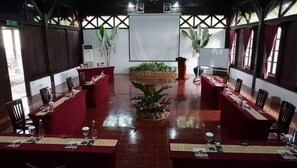 Una sala de conferencias con una mesa central, sillas alrededor y una gran pantalla blanca al frente.