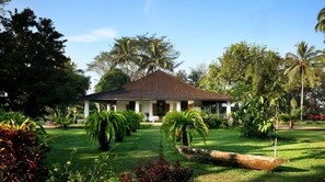 A building with a tiled roof, surrounded by lush greenery and palm trees. - Mesastila Resort and Spa Magelang (Losari)