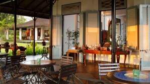 An open-plan living area with a dining table, chairs, and a kitchen area visible through an open doorway. - Mesastila Resort and Spa Magelang (Losari)